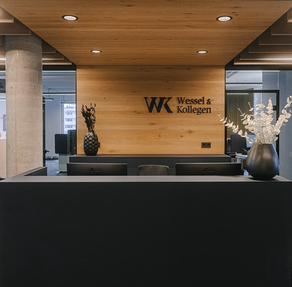 Empfangstheke von Wessel & Kollegen mit modernem Design, Pflanzen und Holzverkleidung.